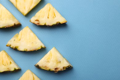 Photo of Pieces of tasty ripe pineapple on light blue background, flat lay. Space for text