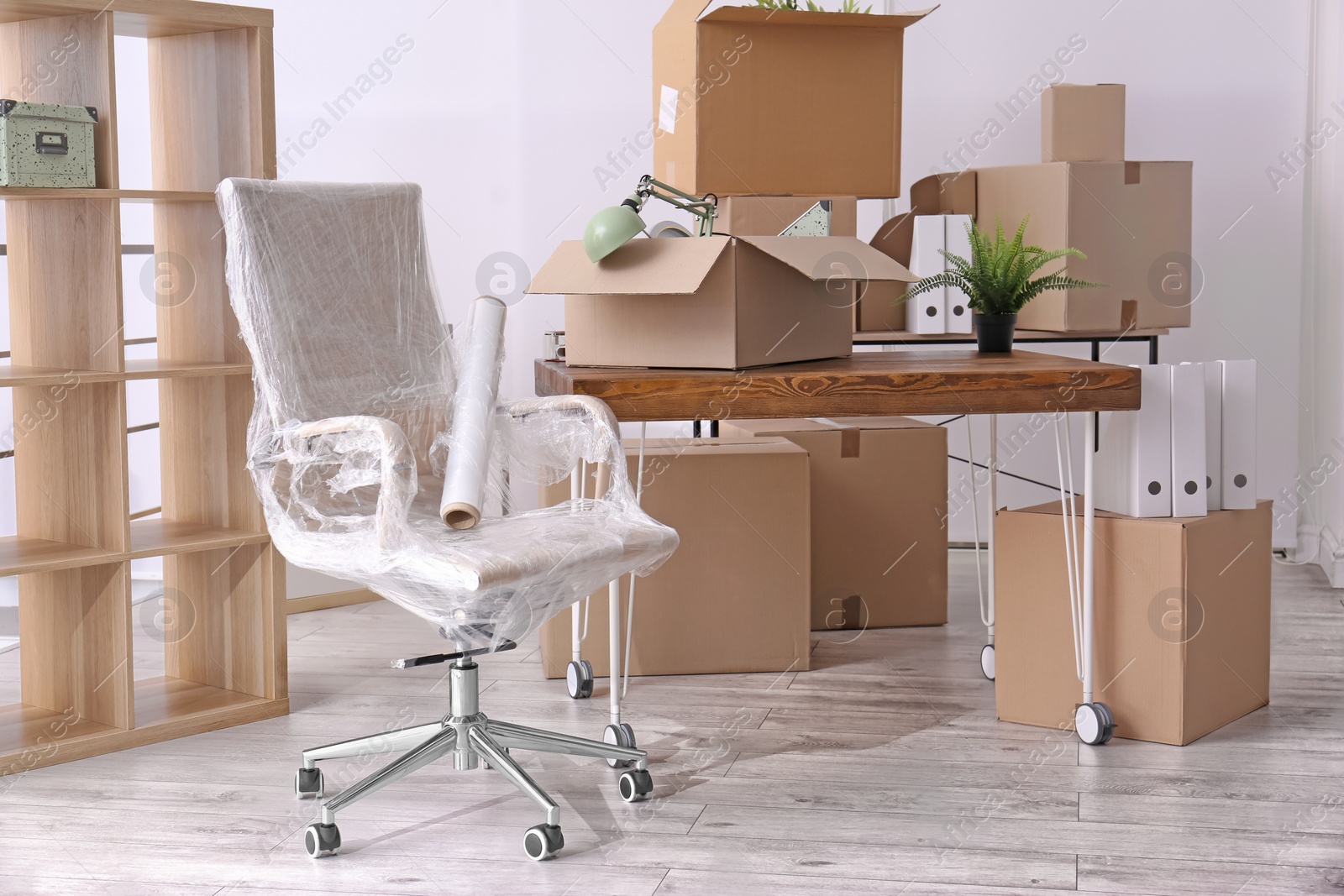 Photo of Armchair and carton boxes with stuff in room. Office move concept