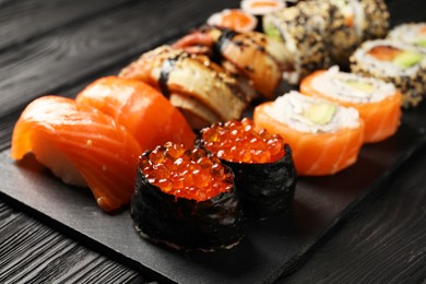 Photo of Set of delicious sushi rolls on black wooden table, closeup