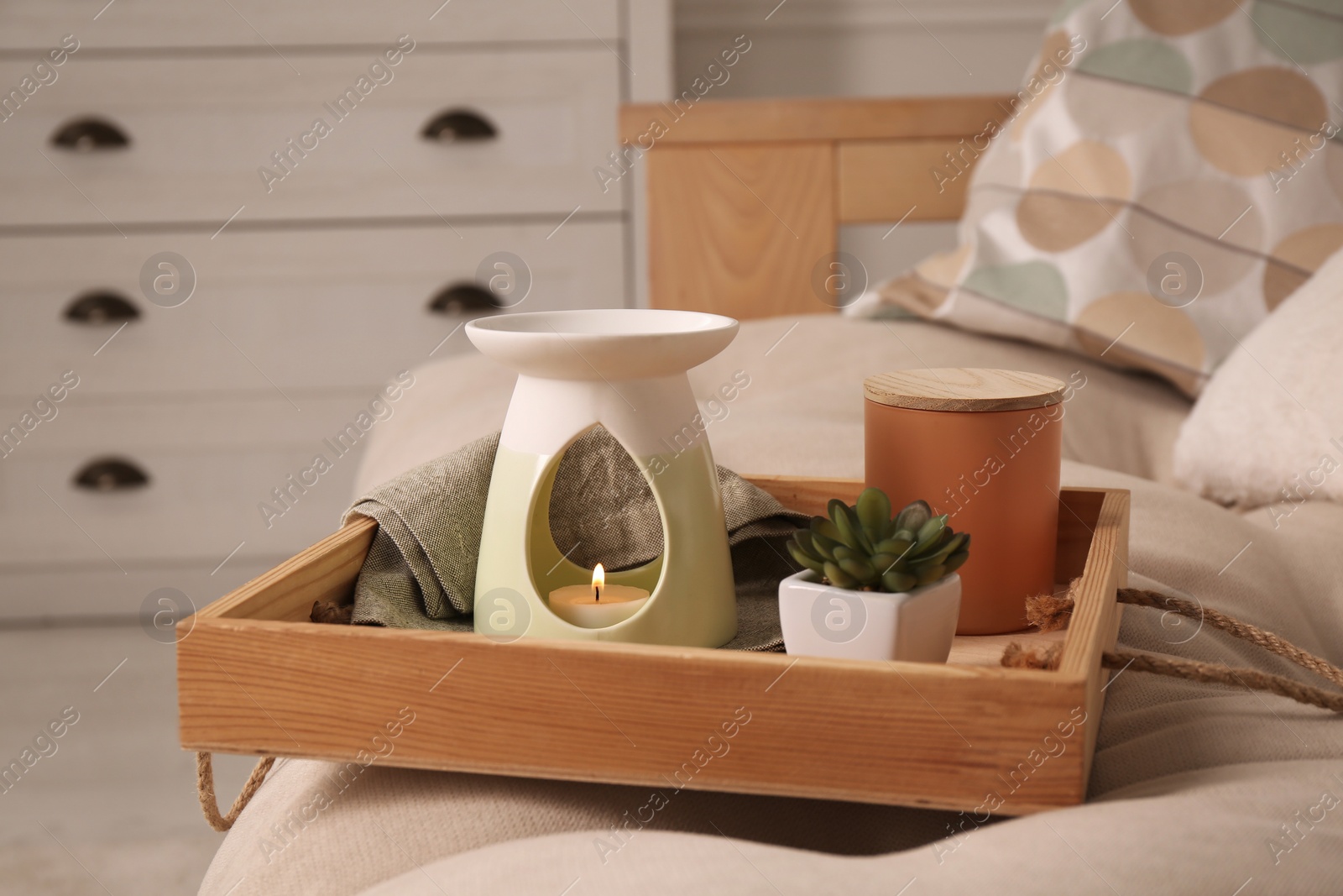 Photo of Tray with stylish aroma lamp and houseplant on sofa in room