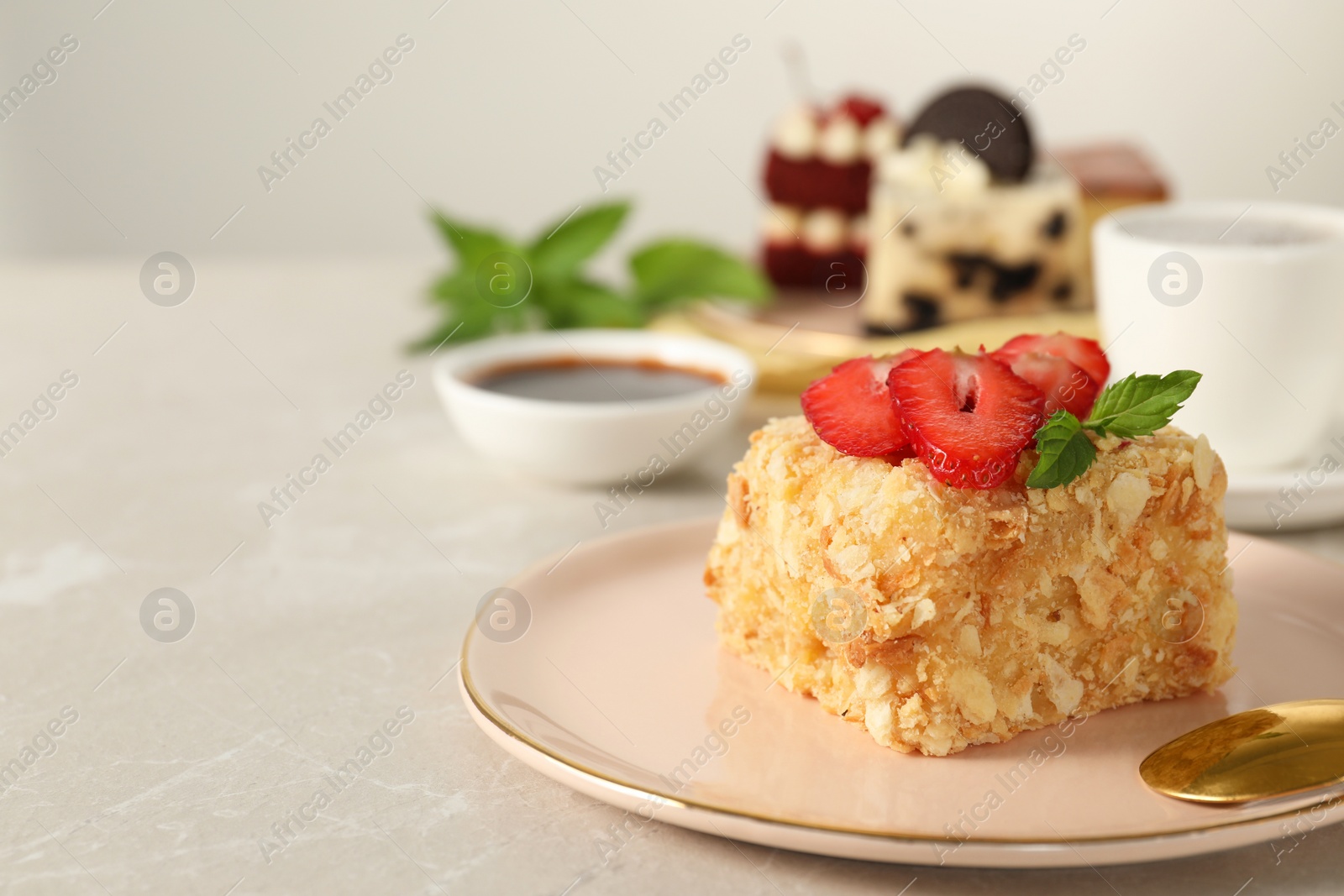 Photo of Piece of delicious Napoleon cake with fresh strawberries on light grey marble table, closeup. Space for text