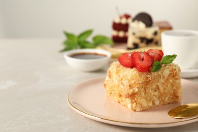 Photo of Piece of delicious Napoleon cake with fresh strawberries on light grey marble table, closeup. Space for text