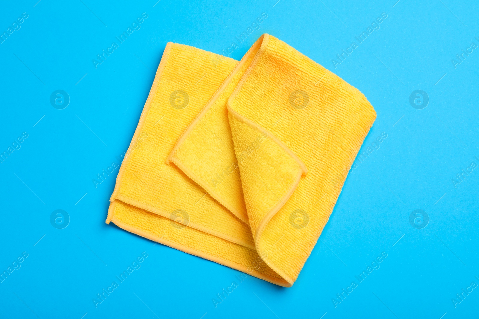 Photo of Orange microfiber cloth on light blue background, top view