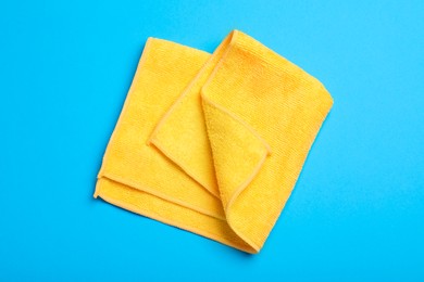 Orange microfiber cloth on light blue background, top view