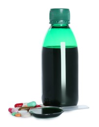 Photo of Bottle of cough syrup, dosing spoon and pills on white background