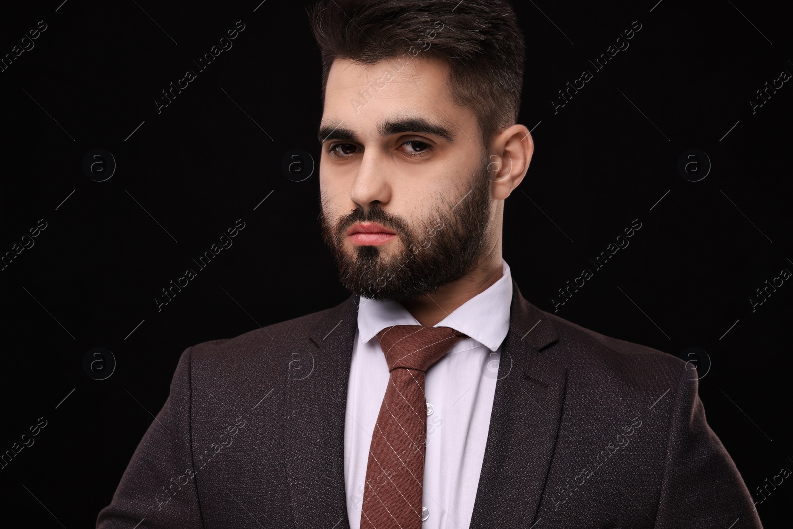 Photo of Handsome businessman in suit and necktie on black background