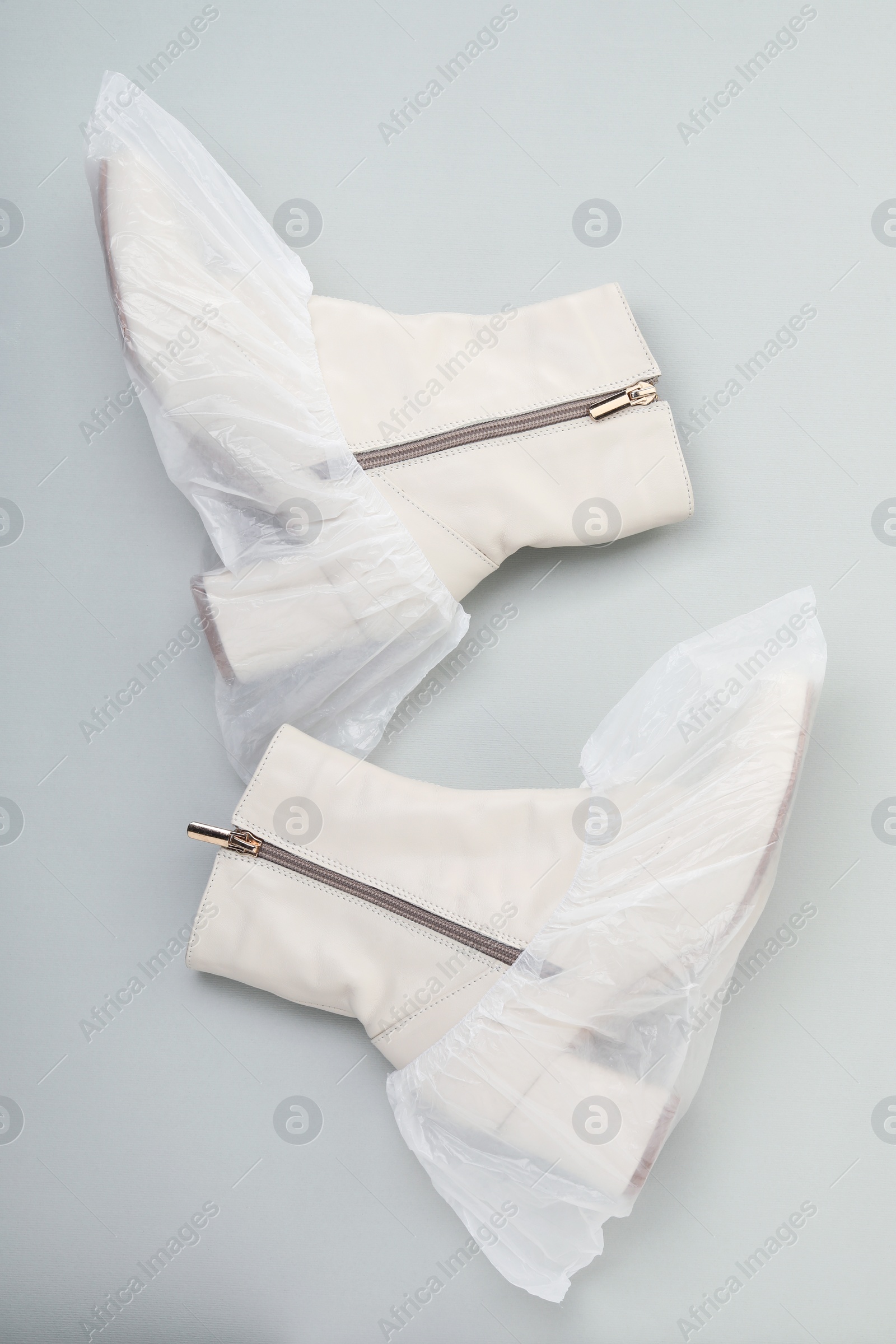 Photo of Women's boots in shoe covers on grey background, top view