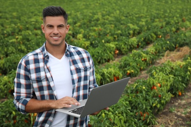 Photo of Man with laptop in field. Agriculture technology