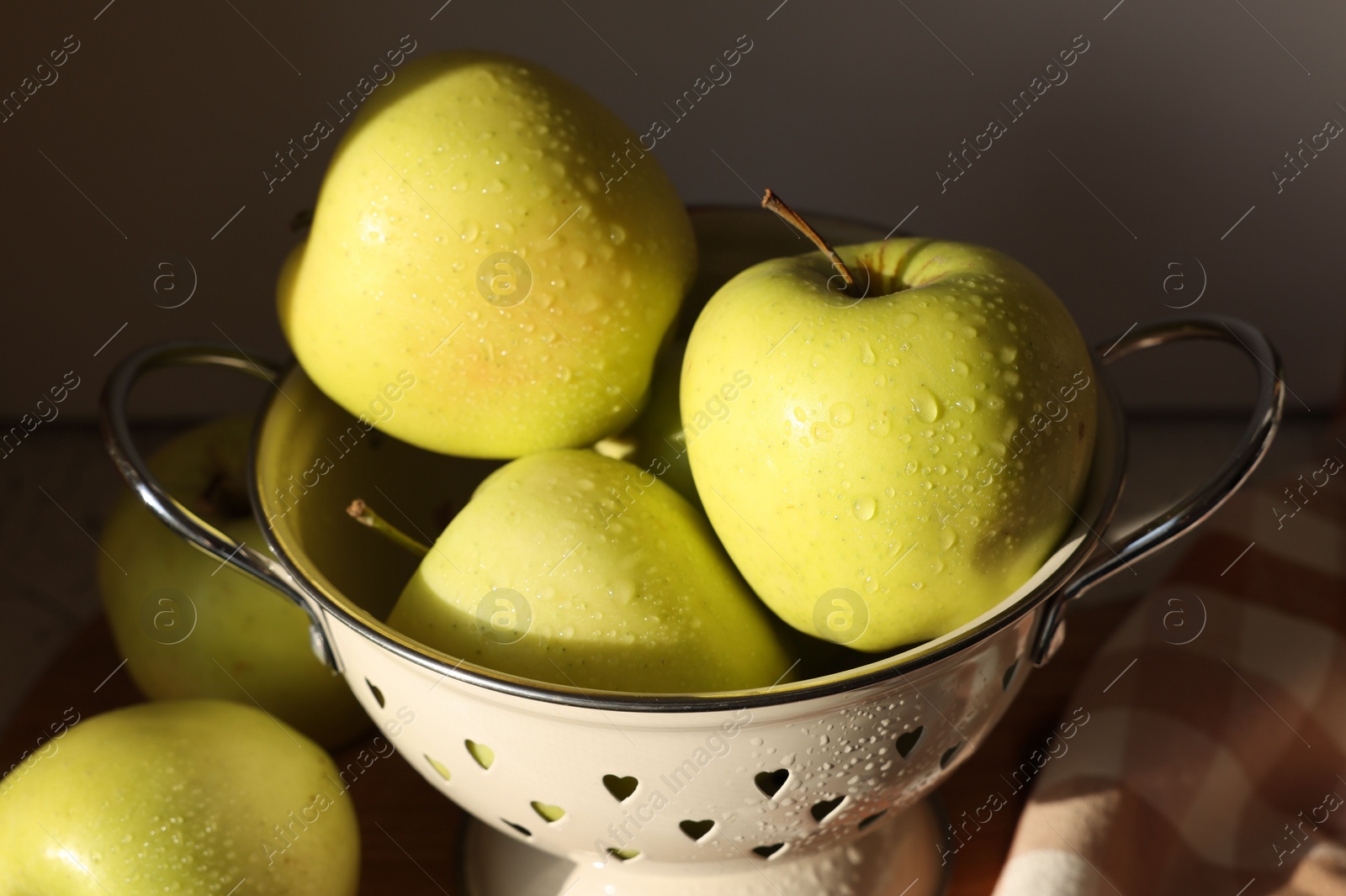 Photo of Fresh wet apples in colander on dark background, closeup