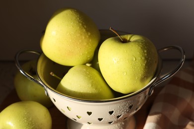 Photo of Fresh wet apples in colander on dark background, closeup