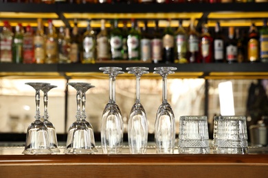 Photo of Different empty clean glasses on counter in bar