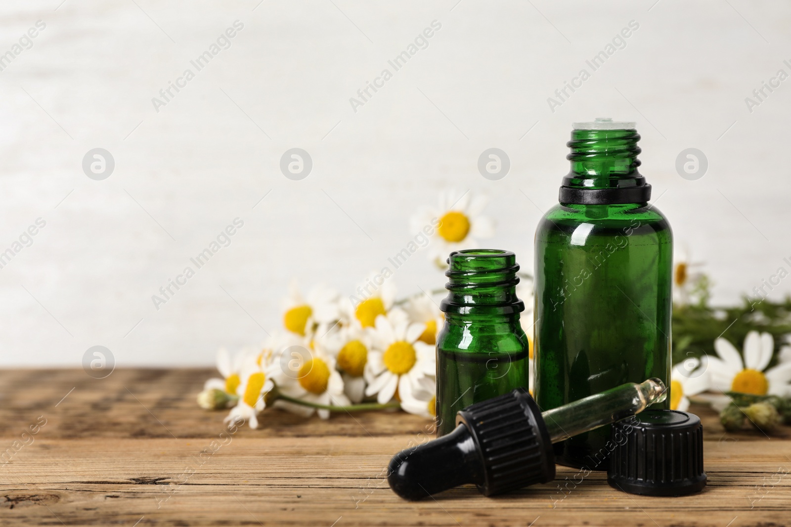 Photo of Composition with bottles of chamomile essential oil on table. Space for text