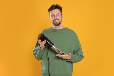 Photo of Smiling man holding sous vide cooker on orange background