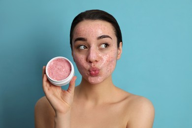 Photo of Woman with pomegranate face mask on light blue background