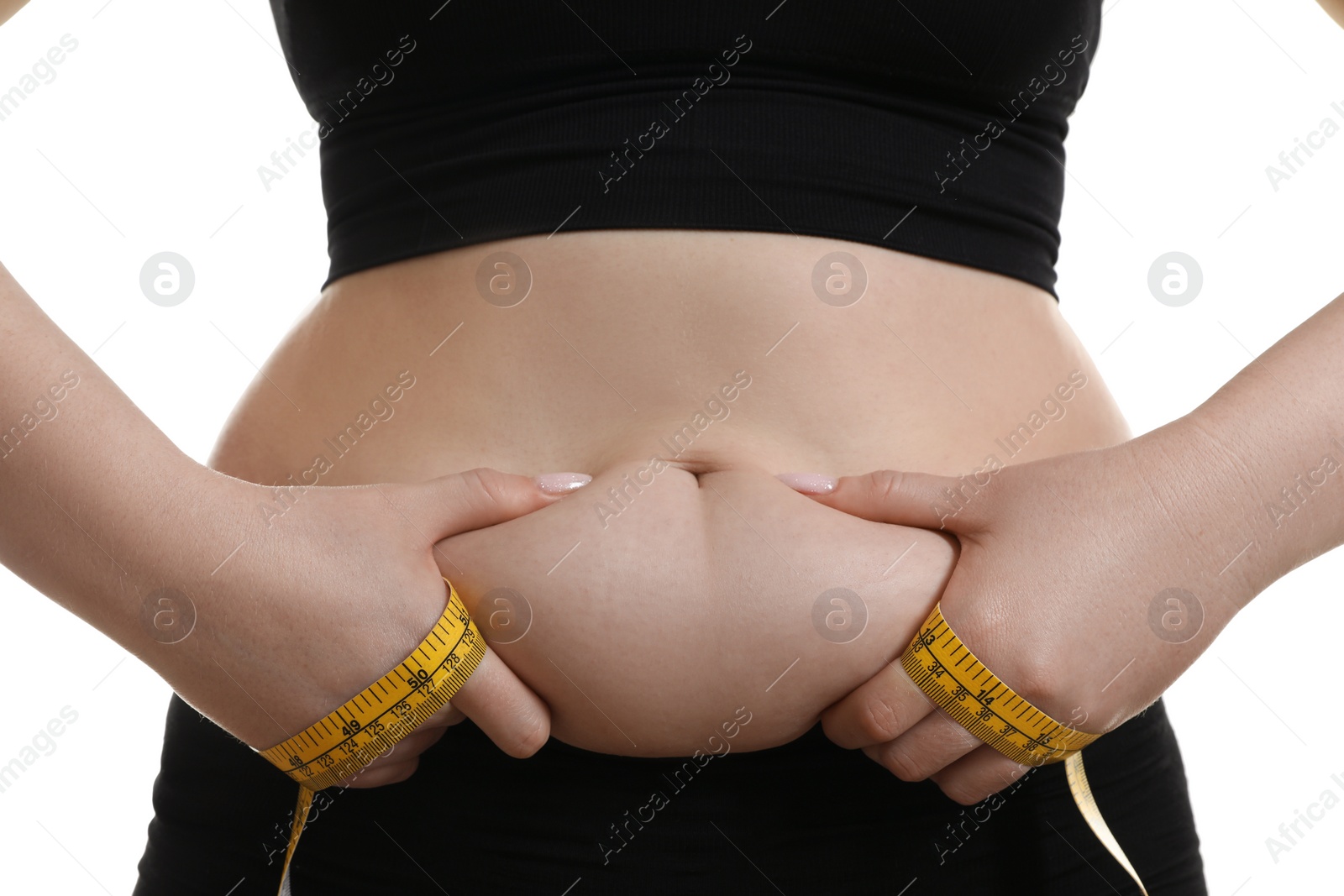 Photo of Woman with measuring tape touching belly fat on white background, closeup. Overweight problem