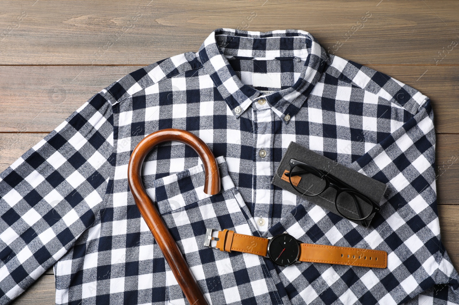 Photo of Stylish outfit with walking cane on wooden background, flat lay