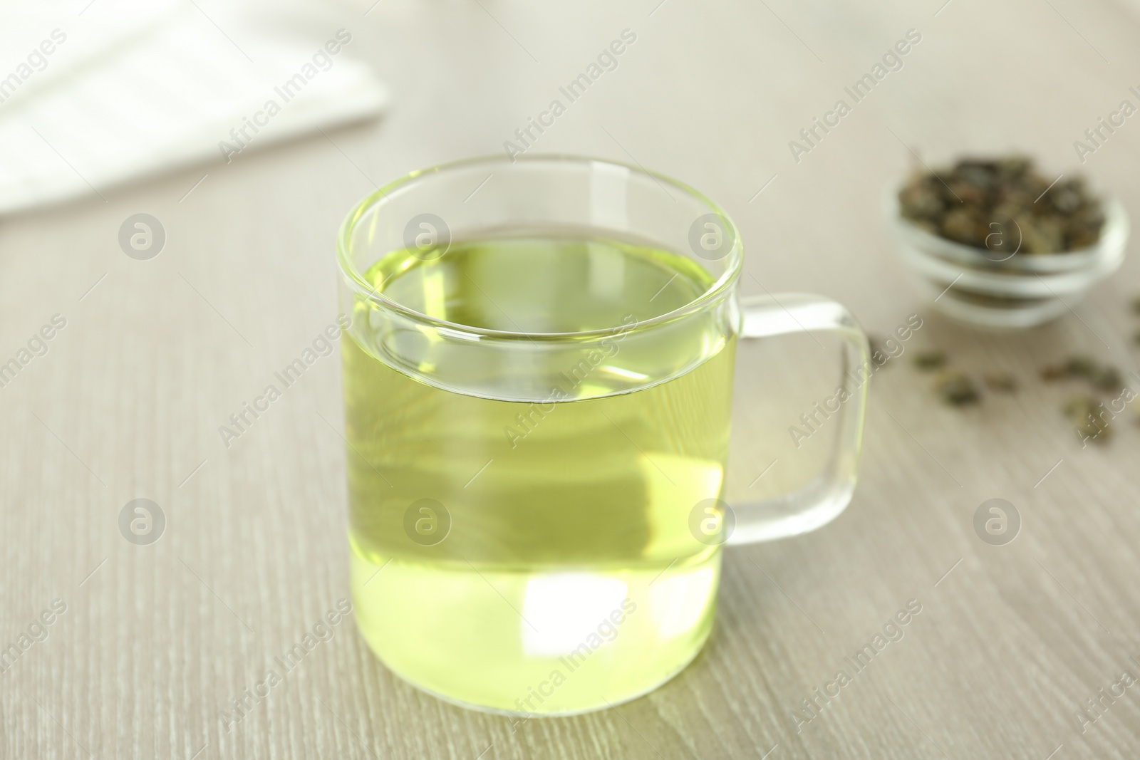 Photo of Cup of aromatic green tea on light wooden table