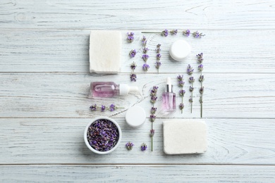 Flat lay composition of handmade soap bars with lavender flowers and ingredients on white wooden background