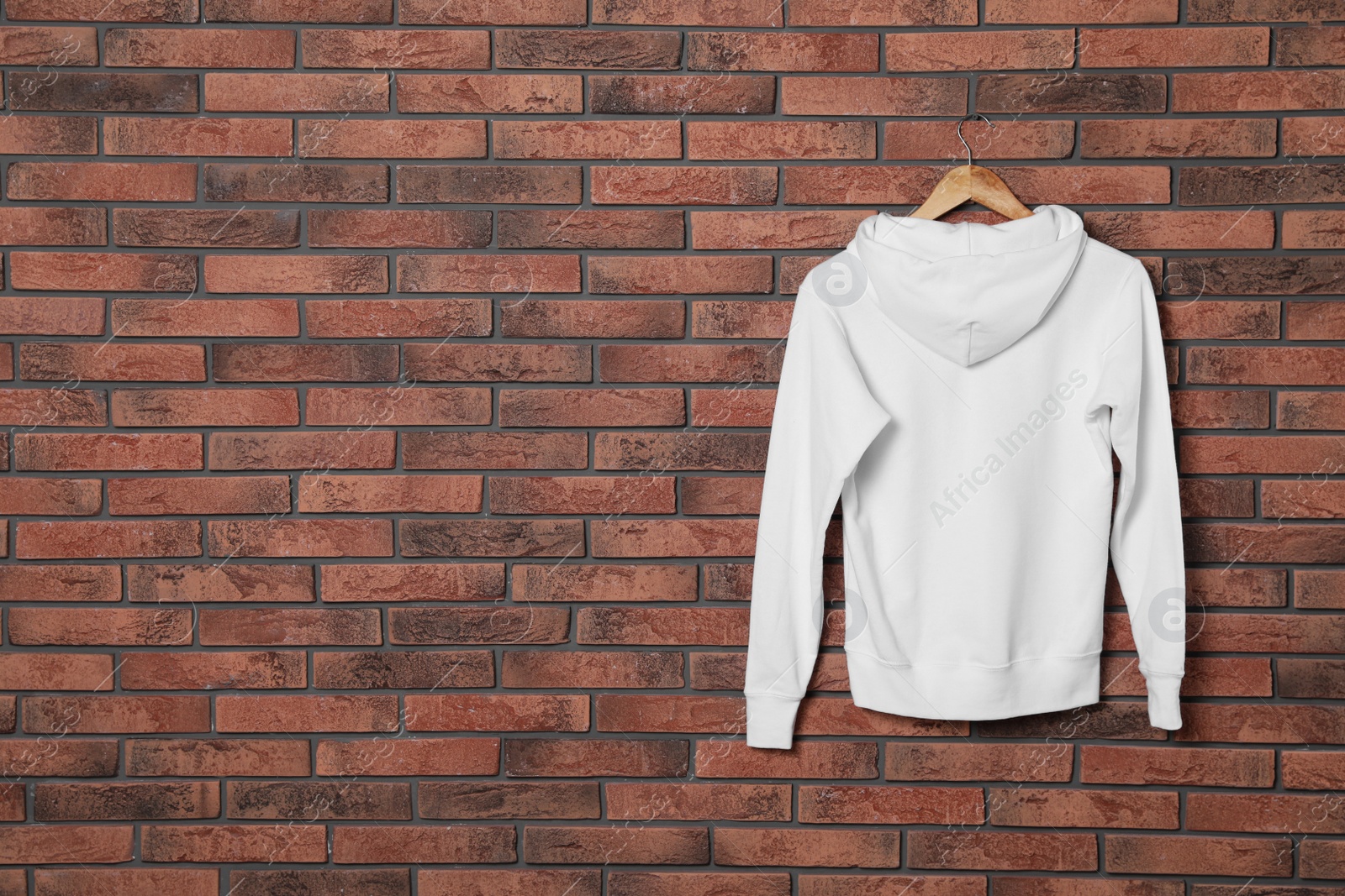 Photo of Hanger with new sweater on brick wall, mock up for design