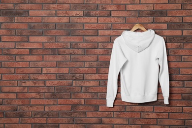 Photo of Hanger with new sweater on brick wall, mock up for design