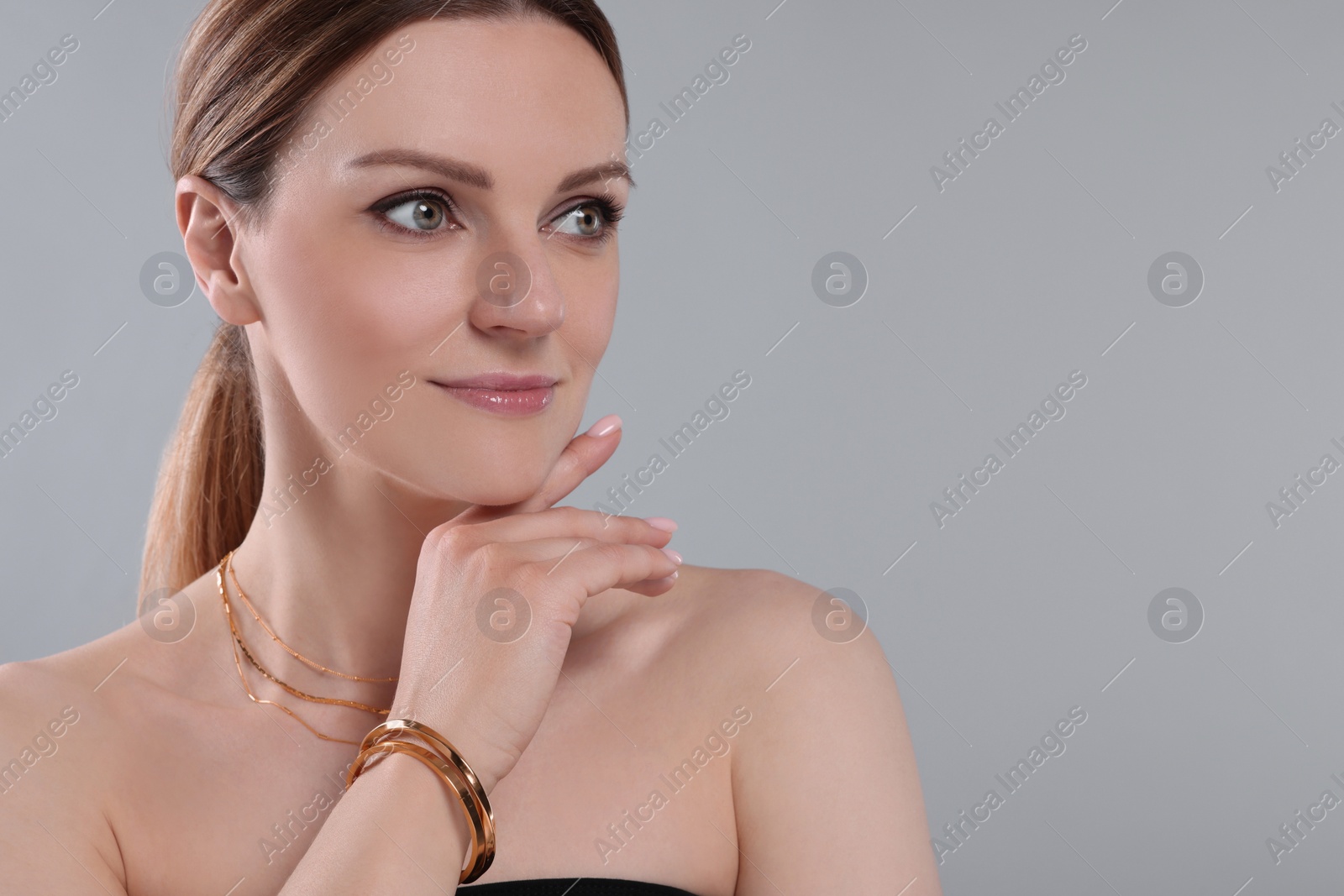 Photo of Beautiful woman with elegant jewelry on light grey background. Space for text