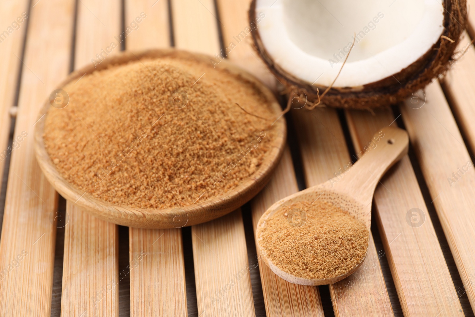 Photo of Coconut sugar, spoon, plate and fruit on wooden table, closeup