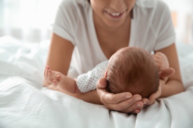 Young woman with her newborn baby on bed, closeup