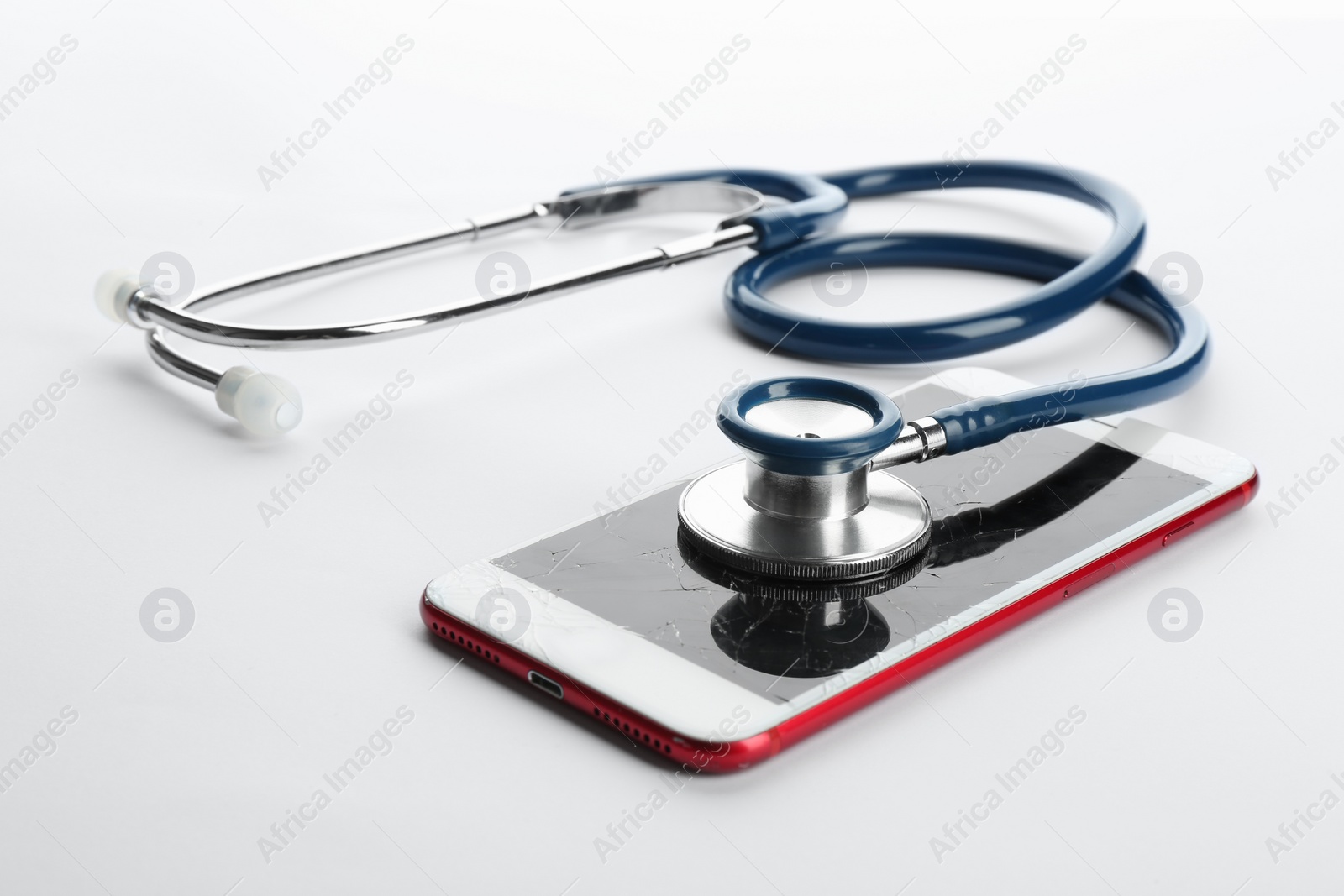 Photo of Modern smartphone with broken display and stethoscope on white background. Device repair service