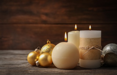 Burning wax candles and Christmas decorations on table