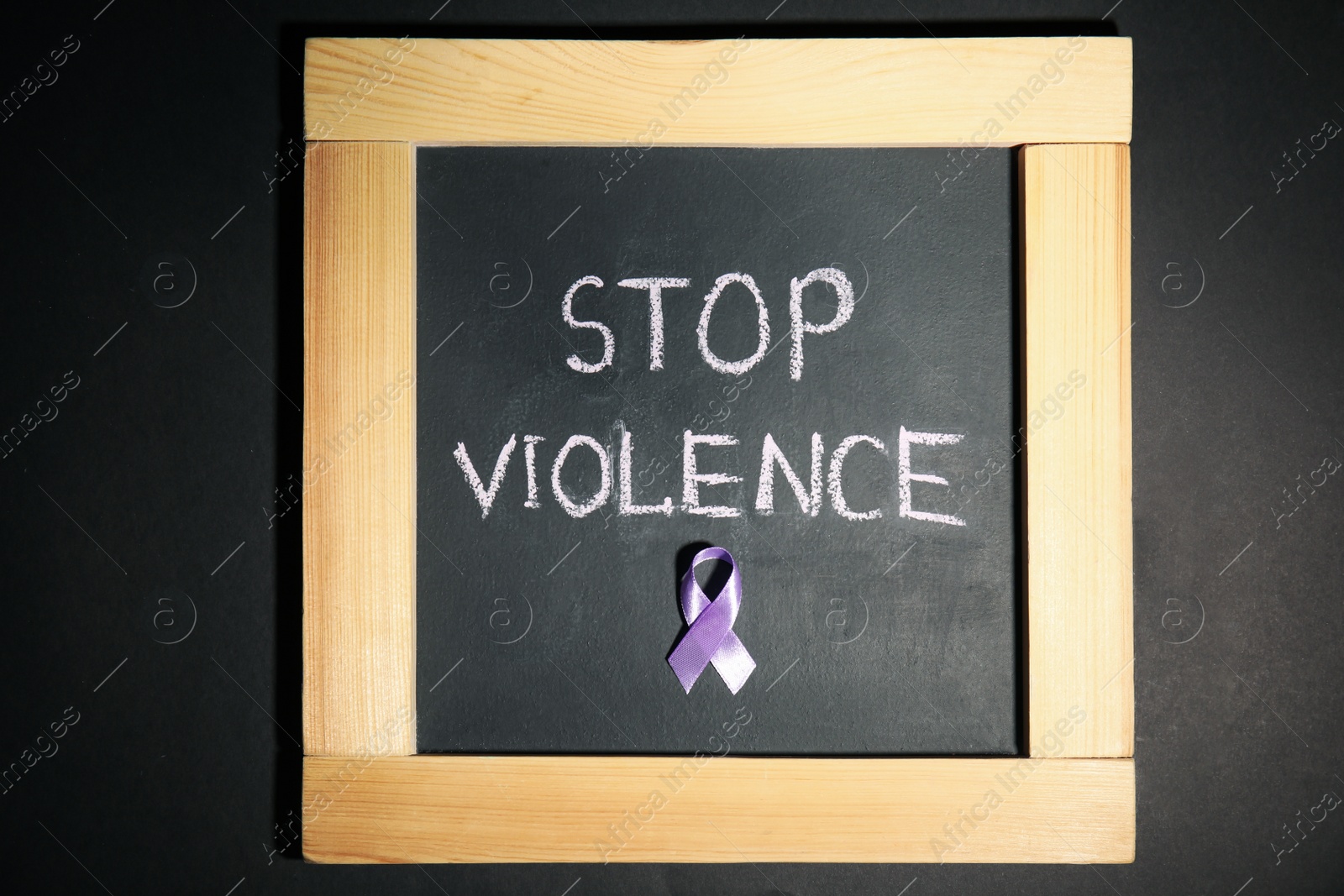 Photo of Chalkboard with purple ribbon and phrase STOP VIOLENCE on black background, top view