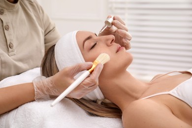 Photo of Young woman during face peeling procedure in salon