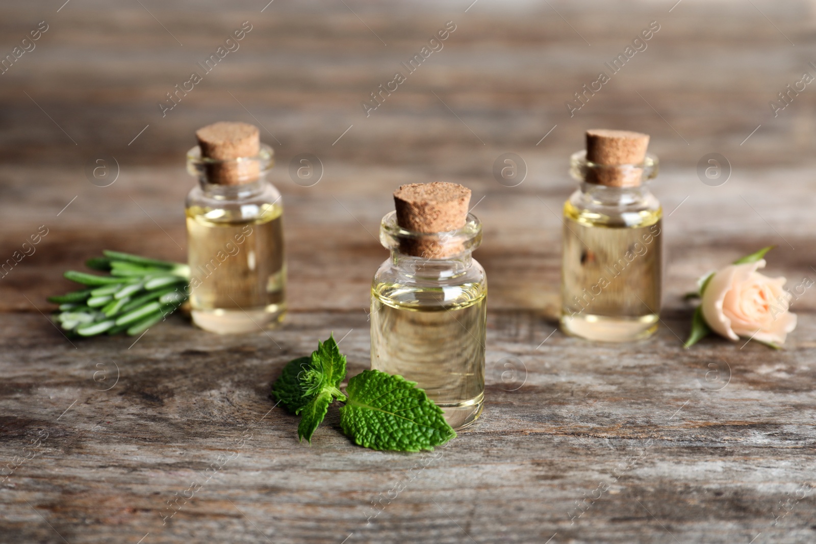 Photo of Different essential oils in glass bottles and ingredients on wooden table