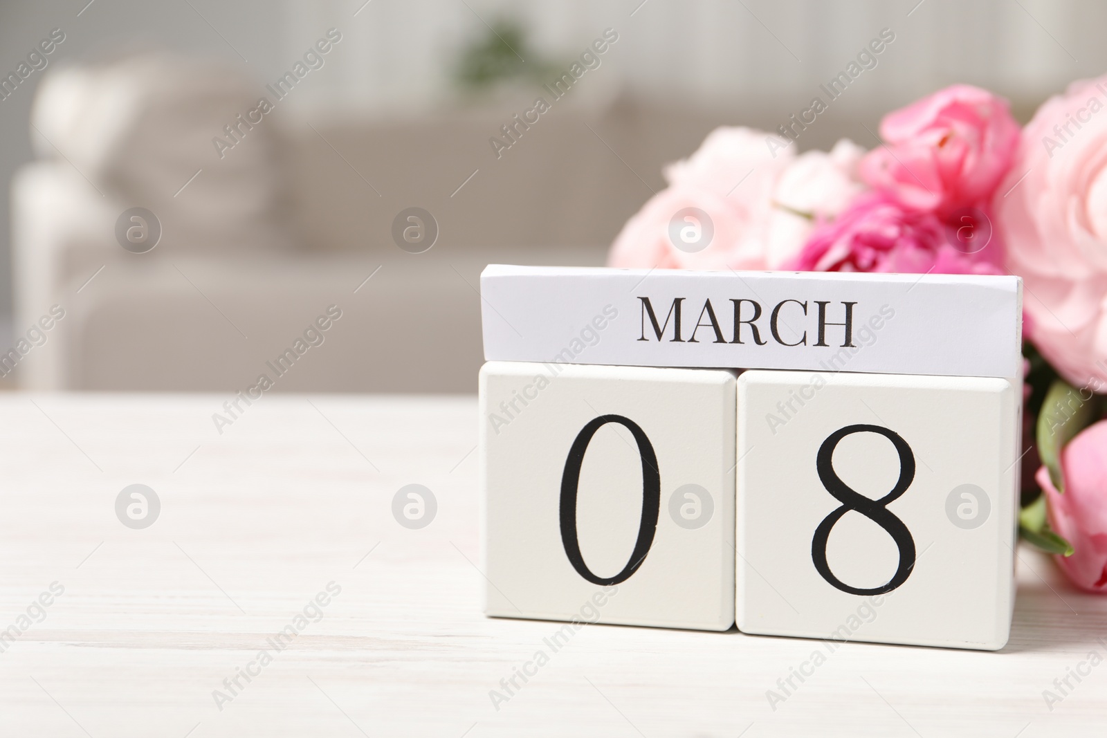 Photo of International Women's day - 8th of March. Block calendar and bouquet of beautiful flowers on white wooden table, closeup. Space for text