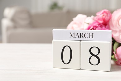 International Women's day - 8th of March. Block calendar and bouquet of beautiful flowers on white wooden table, closeup. Space for text