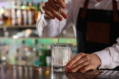 Photo of Bartender making fresh alcoholic cocktail at counter in bar, closeup