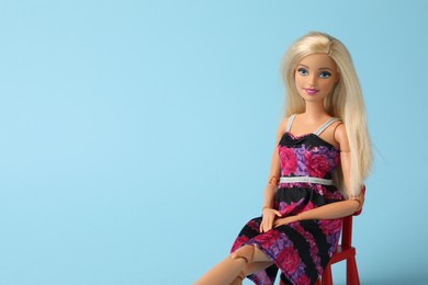 Photo of Mykolaiv, Ukraine - September 4, 2023: Beautiful Barbie doll sitting on chair against light blue background, space for text