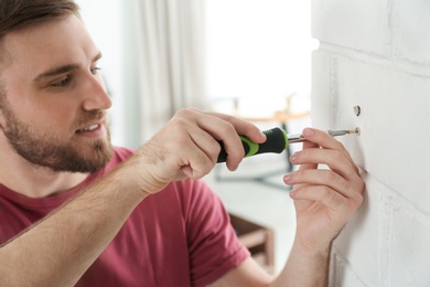 Photo of Young working man using screwdriver at home