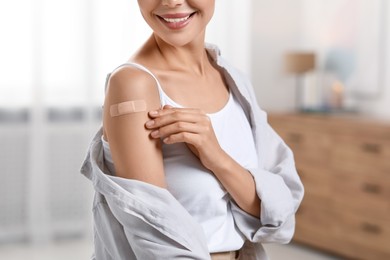 Photo of Woman with sticking plaster on arm after vaccination at home, closeup