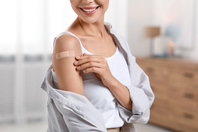 Woman with sticking plaster on arm after vaccination at home, closeup