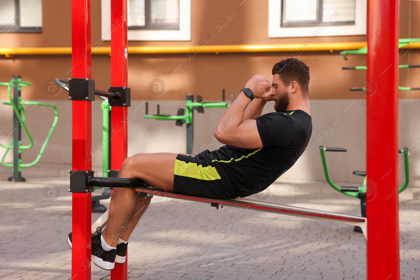 Photo of Man doing abs exercise on bench at outdoor gym