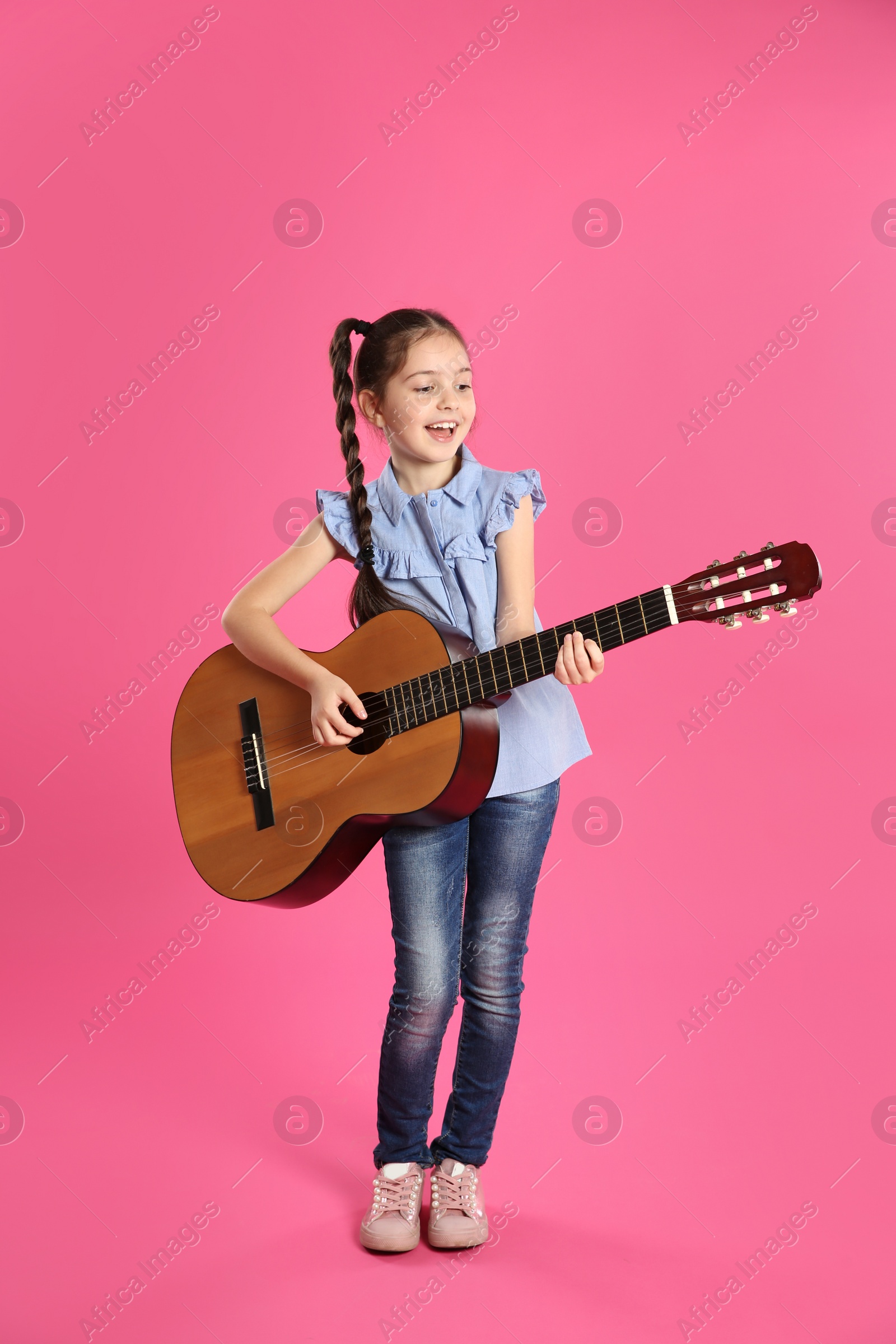 Photo of Cute little girl playing guitar on color background