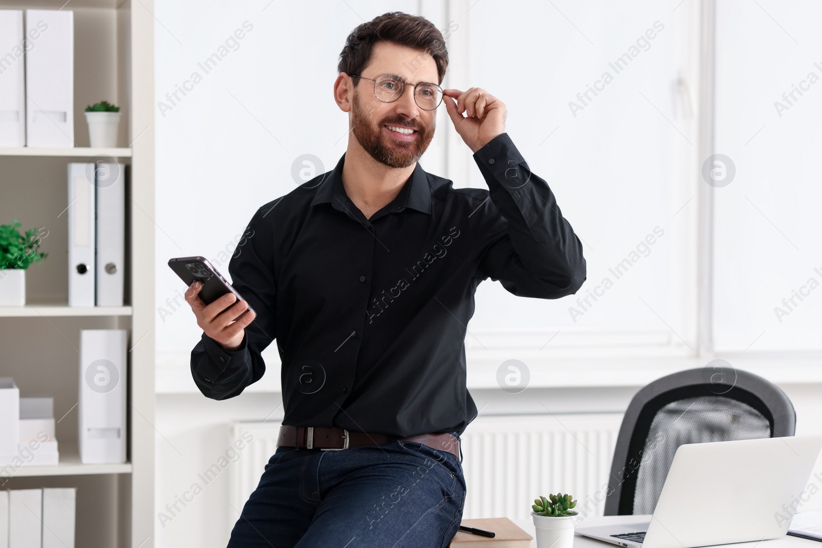 Photo of Smiling man in shirt with smartphone in office