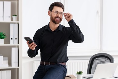 Photo of Smiling man in shirt with smartphone in office