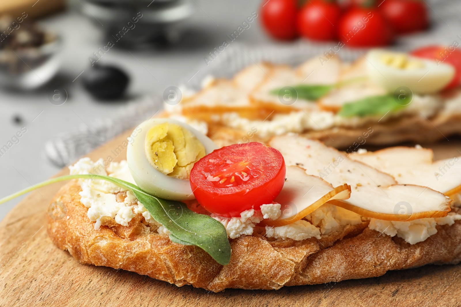 Photo of Board with delicious chicken bruschettas on table, closeup