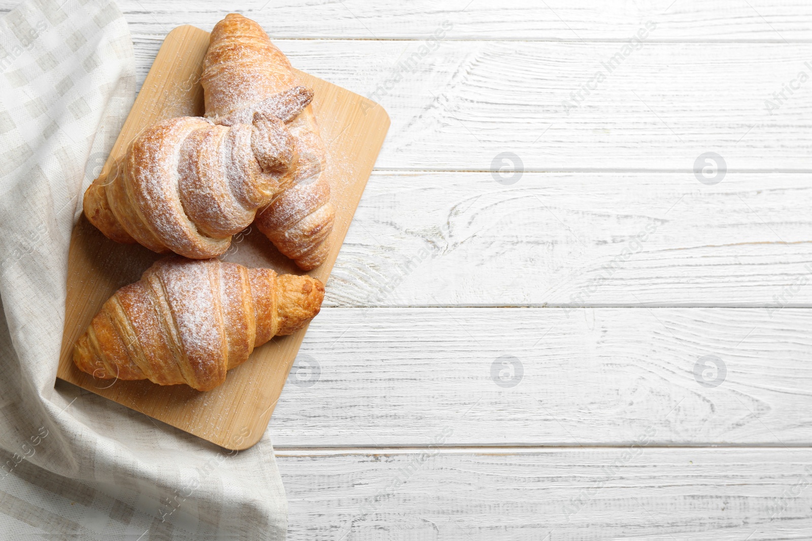 Photo of Board with tasty croissants and space for text on white wooden background, top view. French pastry