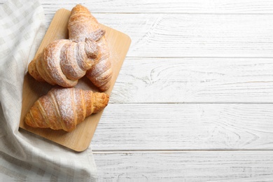 Photo of Board with tasty croissants and space for text on white wooden background, top view. French pastry