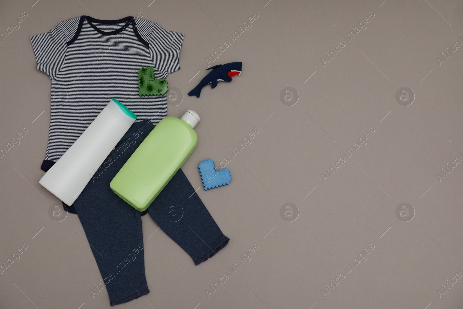 Photo of Bottles of laundry detergents, baby clothes, toy shark and decorative hearts on grey background, flat lay. Space for text