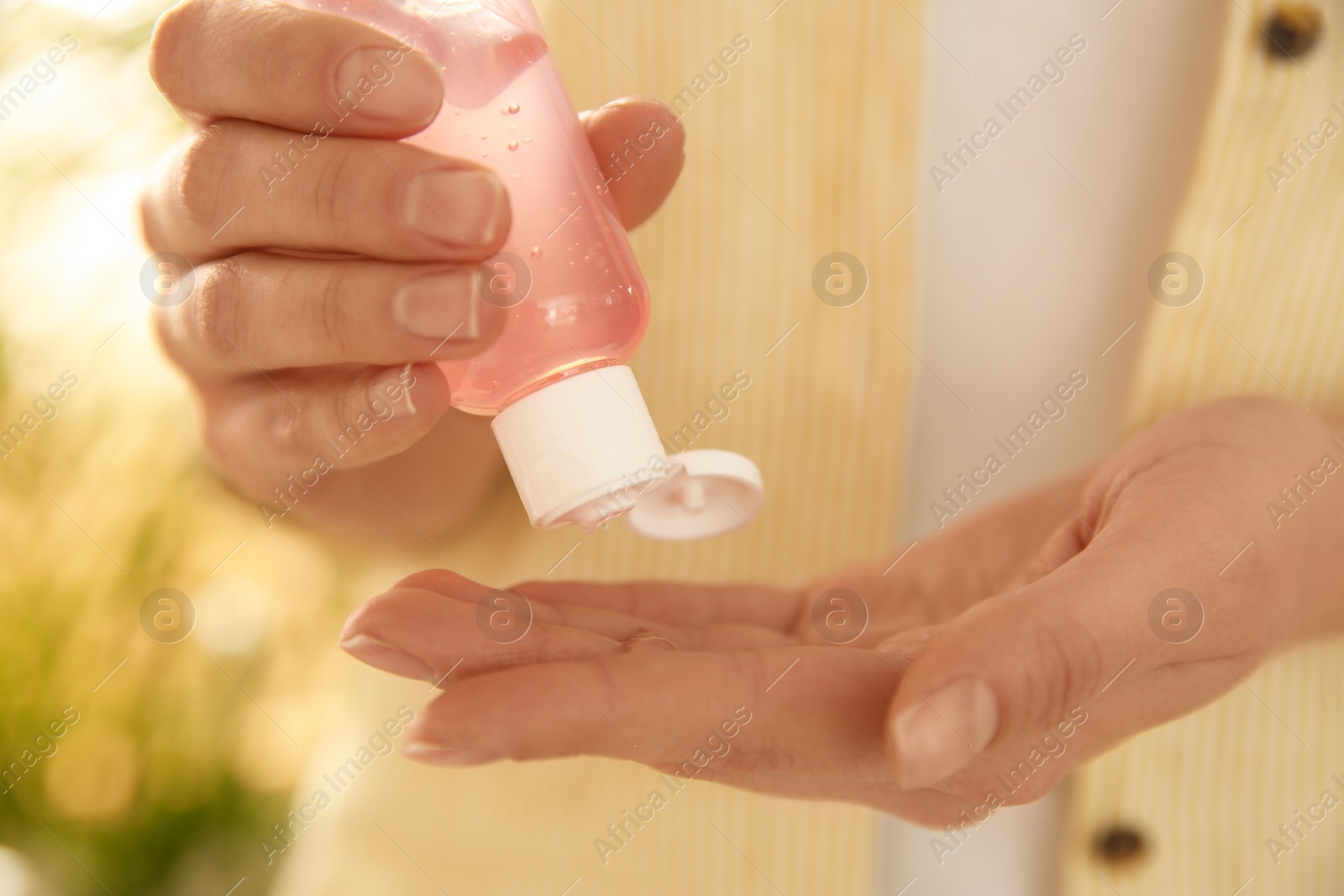 Photo of Young woman applying antiseptic gel outdoors, closeup