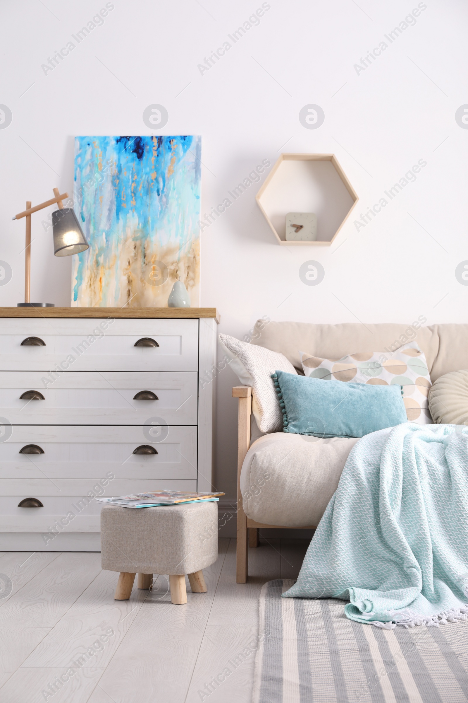 Photo of Stylish living room interior with ottoman, sofa and white wooden chest of drawers