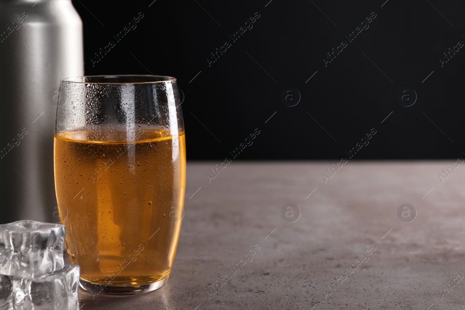 Photo of Energy drink in glass, aluminium can and ice cubes on grey table, closeup. Space for text